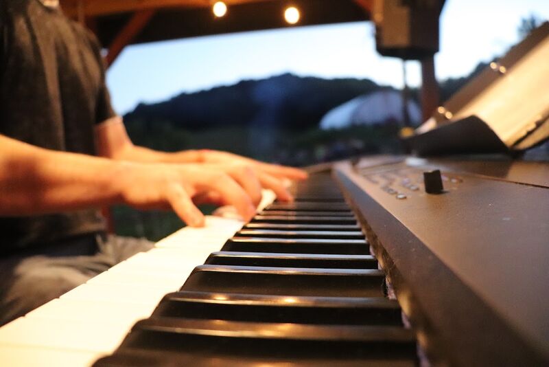 Close-up of hands playing keyboard outdoors with evening bokeh lighting