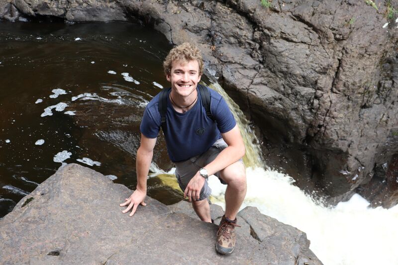 Ryan Howe crouching near a waterfall on a nature hike
